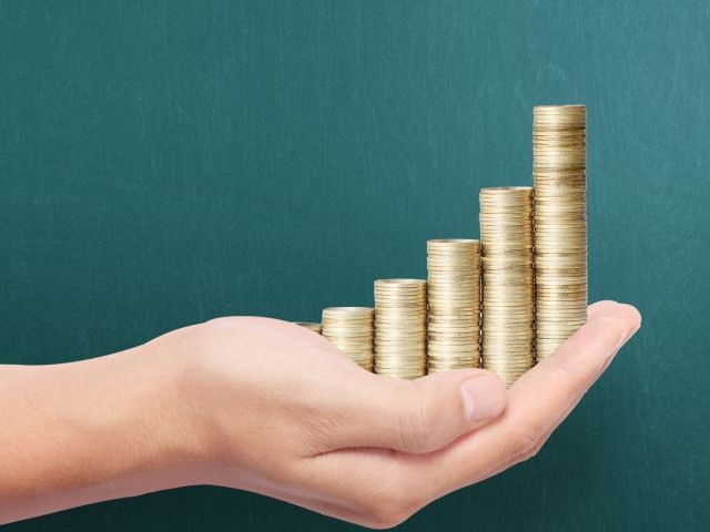 Mit diesen Tipps bekommst Du mehr Geld für Deinen Gebrauchten Hand hält gestapelte Goldmünzen in aufsteigender Reihenfolge, symbolisiert finanzielles Wachstum